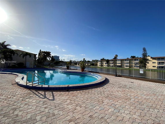 Outdoor swimming pool area with surrounding buildings in the background.