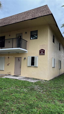 Front view of a two-story building with a balcony and brown roof.