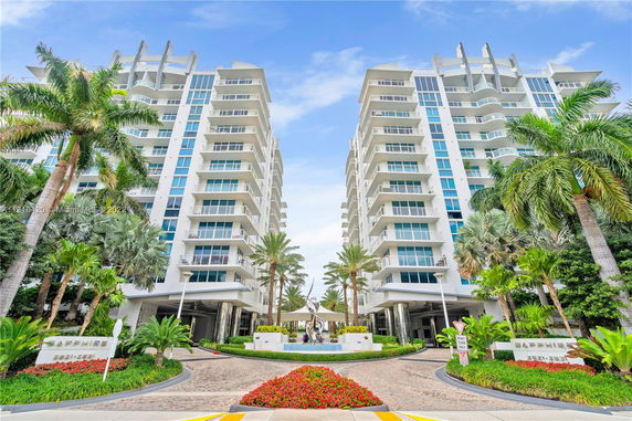 Front view of a modern multi-story residential building with balconies and large windows.