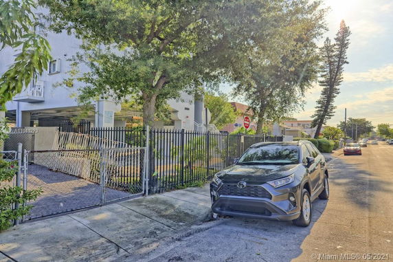 Outdoor parking area with a car parked on the street beside a gated entrance.