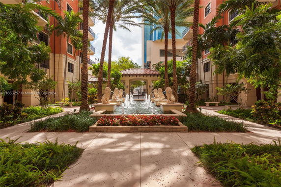 Central courtyard view surrounded by tall buildings with palm trees and a decorative fountain.