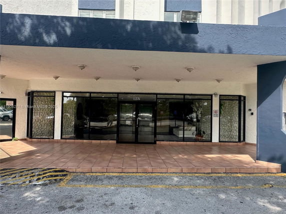Front view of a building entrance with large glass doors and a covered entrance area.