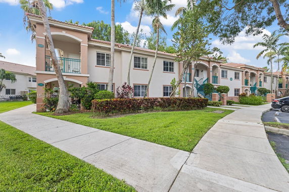 Front view of a two-story residential building with balconies and landscaped surroundings.
