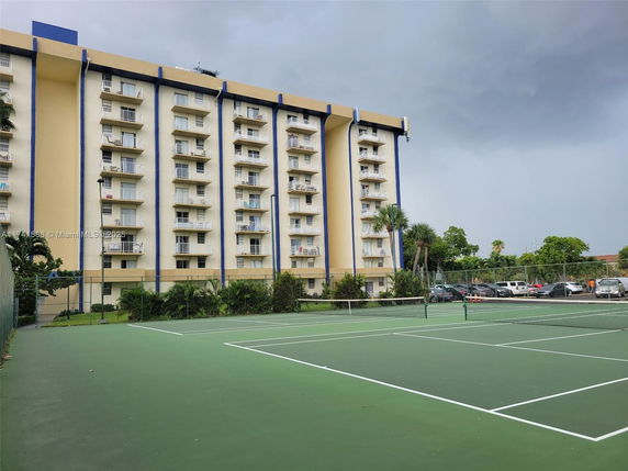 Tennis court in front of a multi-story residential building.