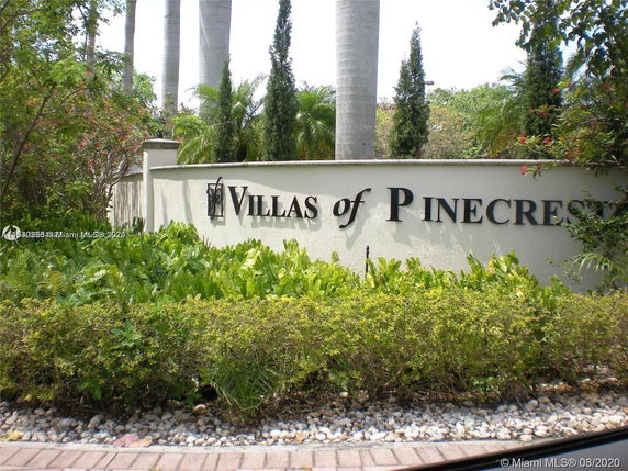 Front view of the Villas of Pinecrest entrance sign surrounded by greenery.