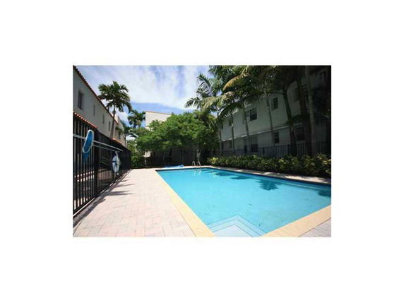 Outdoor swimming pool surrounded by buildings and palm trees.
