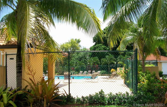 Outdoor swimming pool area with lounge chairs and surrounding palm trees.