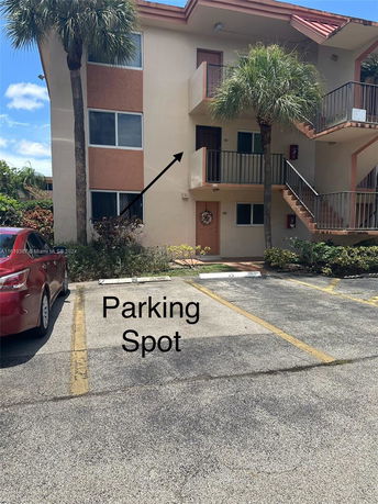 Outdoor parking area in front of a multi-story building with stairs and balconies.