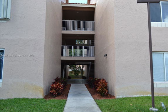Exterior view of a multi-story building with balconies and a central walkway.