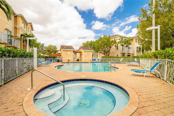 Outdoor swimming pool area with adjacent buildings and lounge chairs.