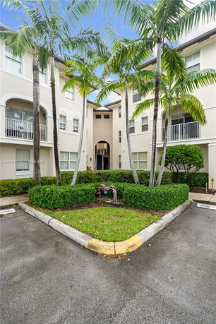 Front view of a multi-story residential building with palm trees.