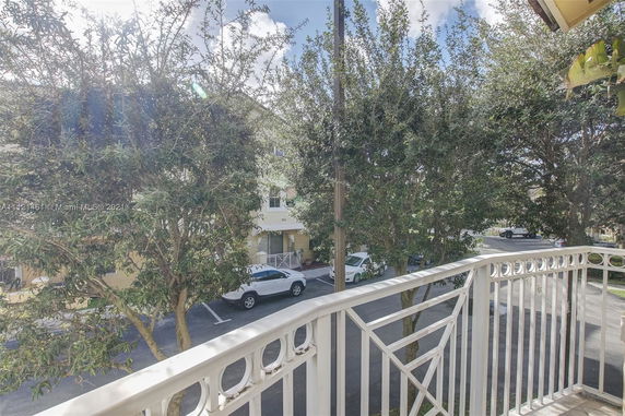 View from a balcony overlooking parked cars and a residential street.
