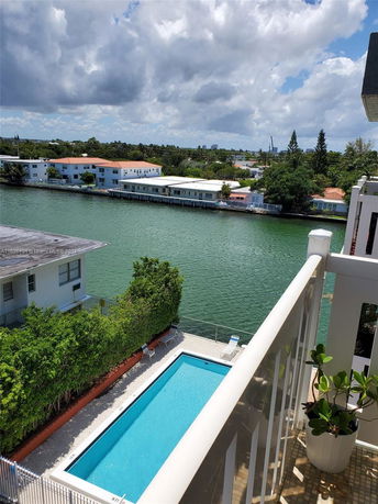 View of a swimming pool and canal with houses on the opposite side.