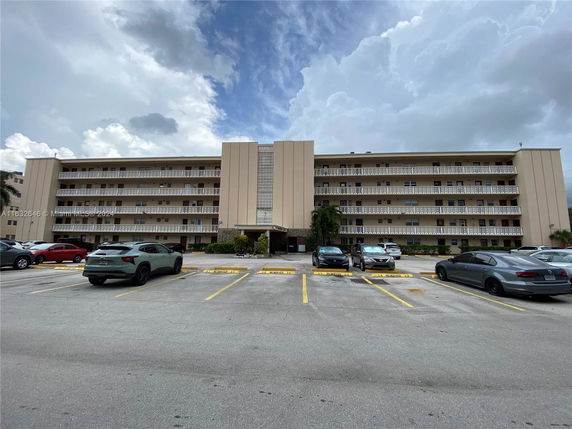 Front view of a multi-story apartment building with parking area in front.