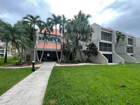 Front view of a multi-story building with palm trees and a pathway leading to the entrance.