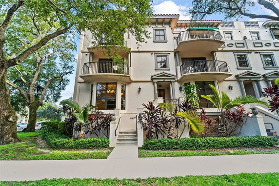 Front view of a multi-story townhouse with balconies and landscaped entrance.