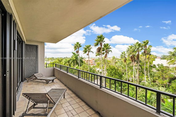 Balcony view overlooking palm trees and distant buildings.