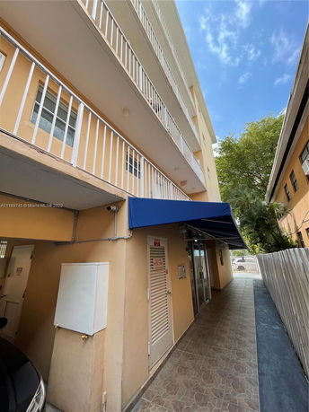 Front view of a multi-story building with a blue awning and balconies.