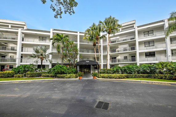 Front view of a multi-story residential building with balconies and a canopy entrance.