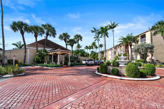 Front view of a building with palm trees and a driveway.