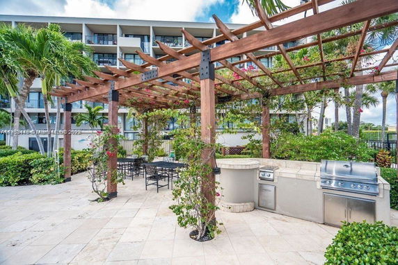 Outdoor area with a wooden pergola and barbecue setup in front of a multi-story building.