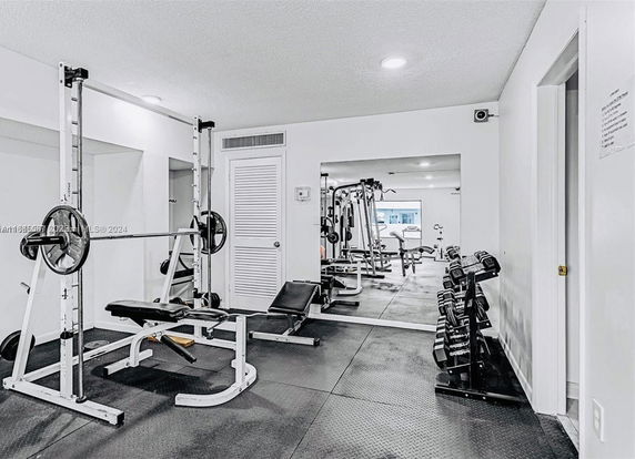 Indoor gym area with exercise equipment and mirrors on the wall.
