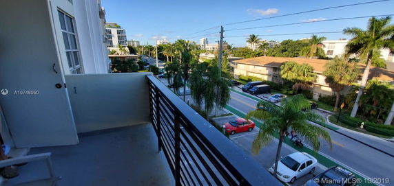 Balcony view looking over a street with palm trees and surrounding buildings.