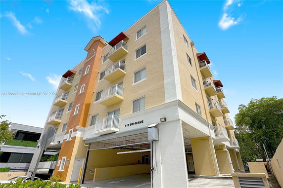 Front view of a multi-story building with balconies and a covered parking area.