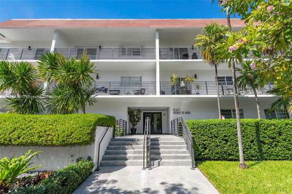 Front view of a multi-story residential building with balconies and a central entrance.