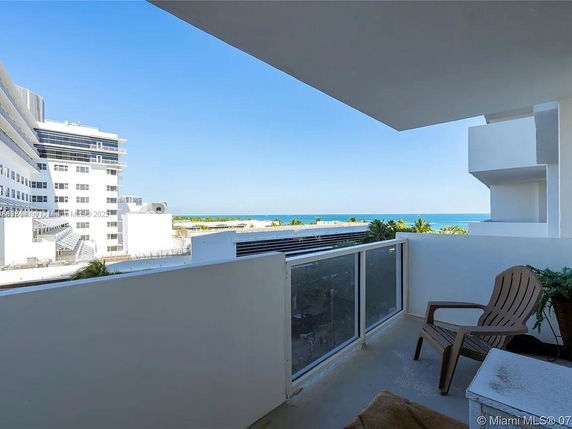 View from a balcony overlooking buildings and the ocean in the background.