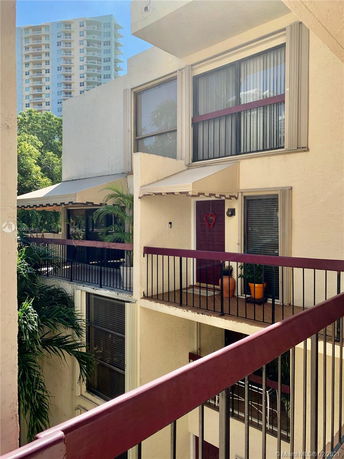 View of a multi-story building with balconies and nearby high-rise building.