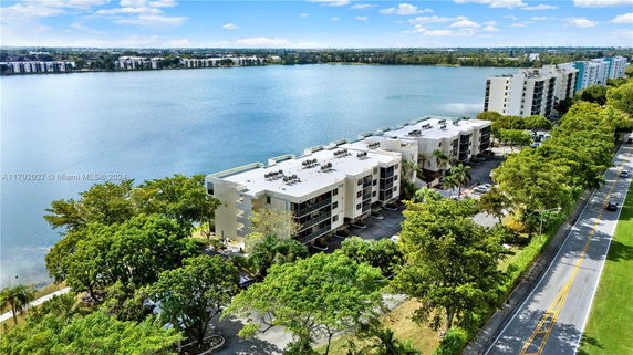 Aerial view of multi-story buildings by a waterfront with visible rooftops containing equipment.