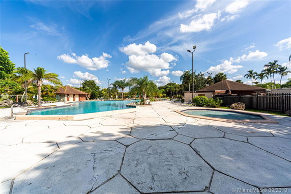 Outdoor swimming pool area with surrounding palm trees and lounge chairs.