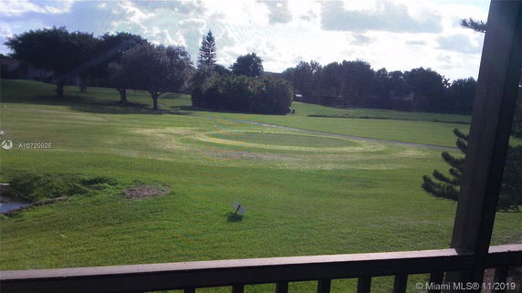 View of a grassy field with trees in the background.