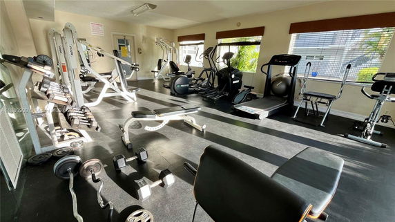 Room with various gym equipment including treadmills, weights, and exercise machines.