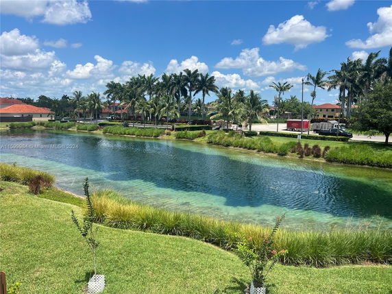 View of a waterway with palm trees and buildings in the background.