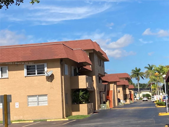 Front view of a two-story residential building with red roofs and beige walls.