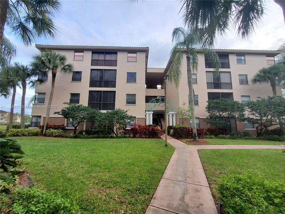 Front view of a multi-story residential building with a landscaped entrance.