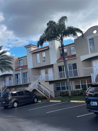 Front view of a multi-story residential building with balconies and exterior stairs.