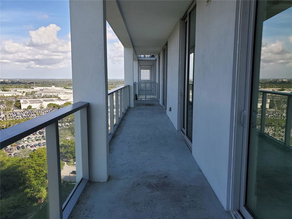 Balcony of a high-rise building with clear glass railings overlooking a cityscape.