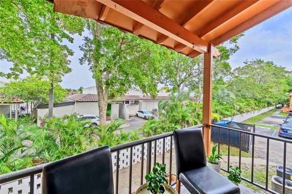 View from a balcony showing parked cars and lush greenery.