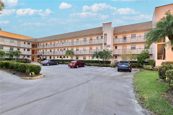 Front view of a multi-story building with an open parking area in front.