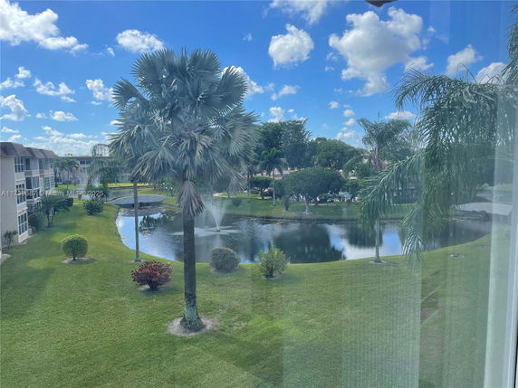 View of landscaped area with small pond and fountain, surrounded by greenery and trees.