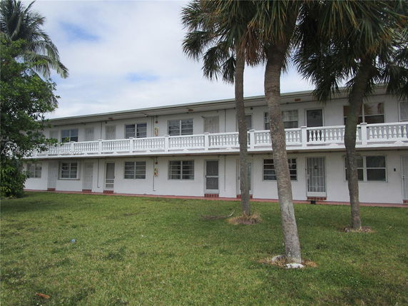 Front view of a two-story building with a balcony and multiple windows.