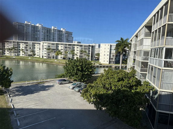 View of residential buildings surrounding a water body with a parking area in the foreground.