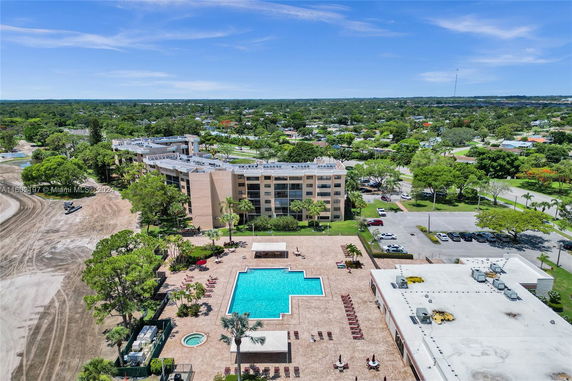 Aerial view of a multi-story apartment complex with a central swimming pool area and surrounding greenery.