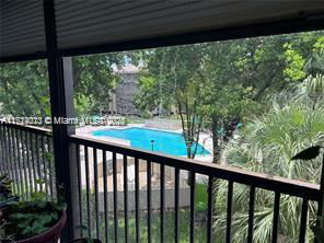 View of a swimming pool surrounded by vegetation seen from a balcony.