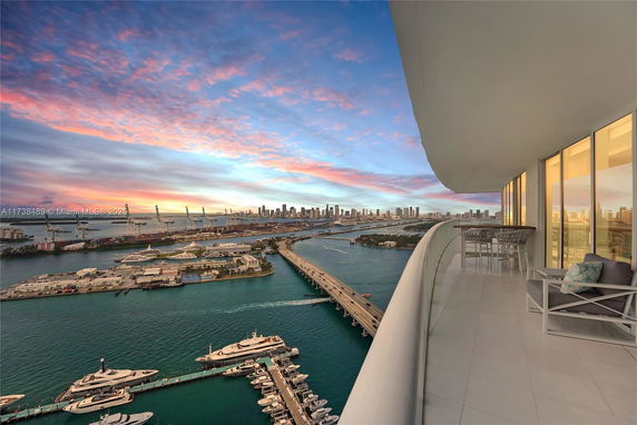 Panoramic view from a high-rise building showcasing waterfront and city skyline during sunset.