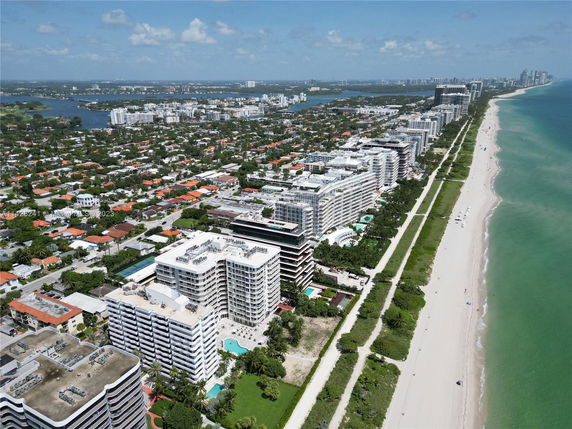 View of beachfront buildings and coastline with a cityscape in the background.