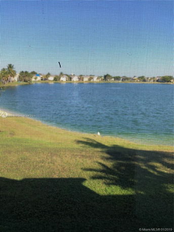 View of a large body of water with houses and trees in the distance.